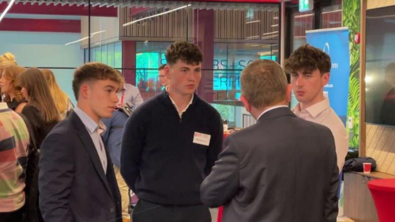 students at an event in a room talking to an employer